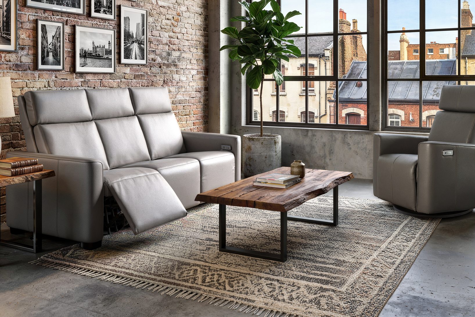 Un sofa inclinable gris et un fauteuil pivotant de la collection Zenith dans un loft de brique, grandes fenêtres à carreaux